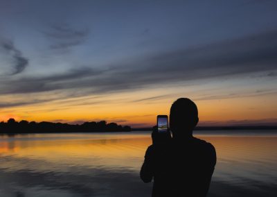 A person taking a photo of a beautiful sunset over the water