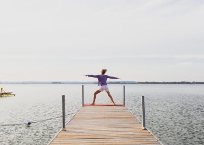 A woman doing yoga at the end of a dock over the water